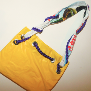 cartera diseñada a partir de inflable pinchado de pileta amarillo y reutilizado con tira de pláticos de descarte y cordón violeta tejido al crochet