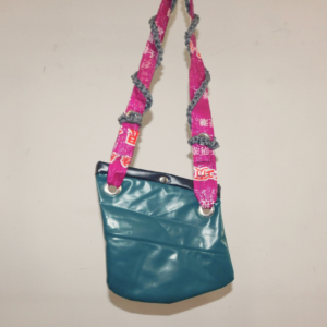 cartera diseñada a partir de colchón inflable pinchado pvc reutilizado color verde y reutilizado con tira hecha de plástico de descarte magenta con inscripciones acompadañada de cordón gris tejido al crochet